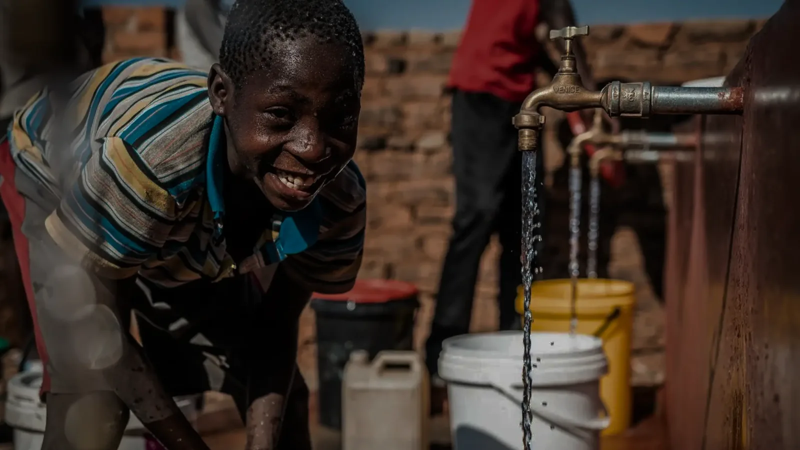 Documentary still of a boy at a water tap in Zimbabwe